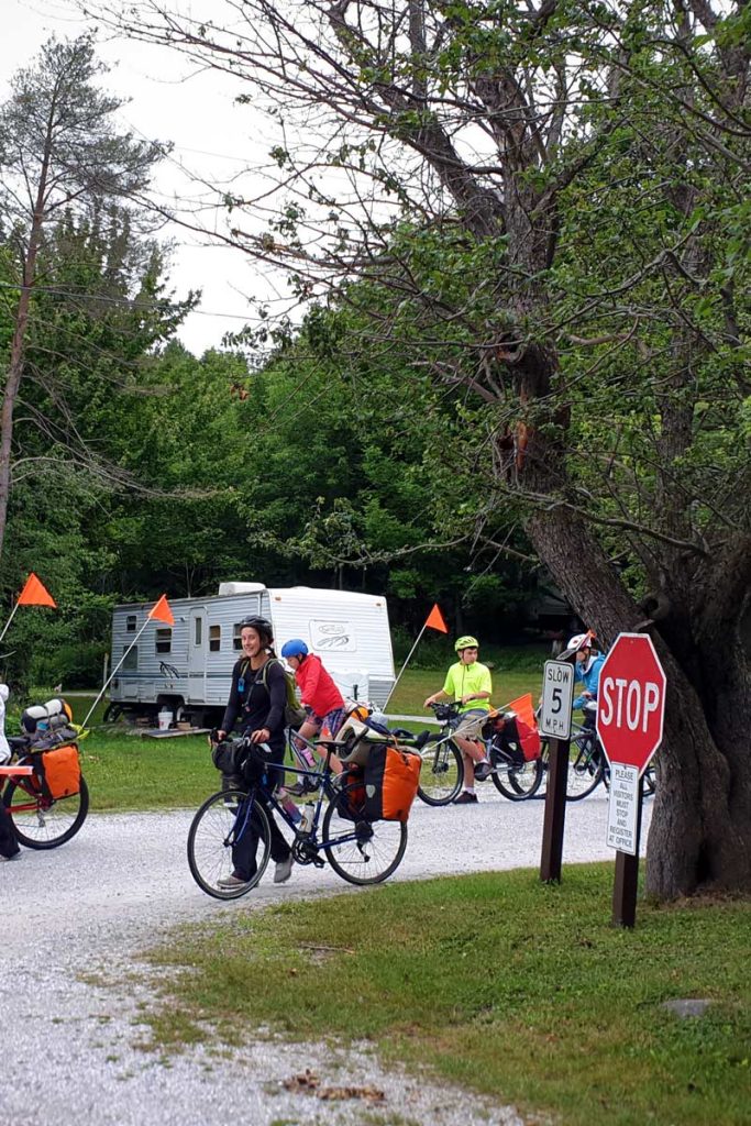 a group of bikers with a woman in a helmet smiling at the camera at maple grove campground