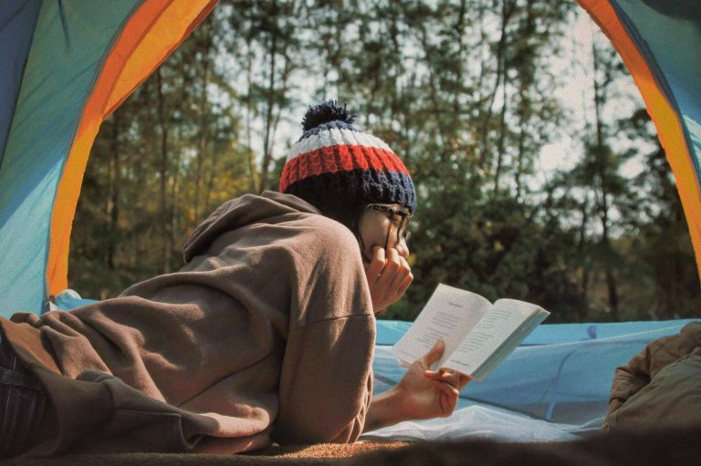 young woman reading inside a tent